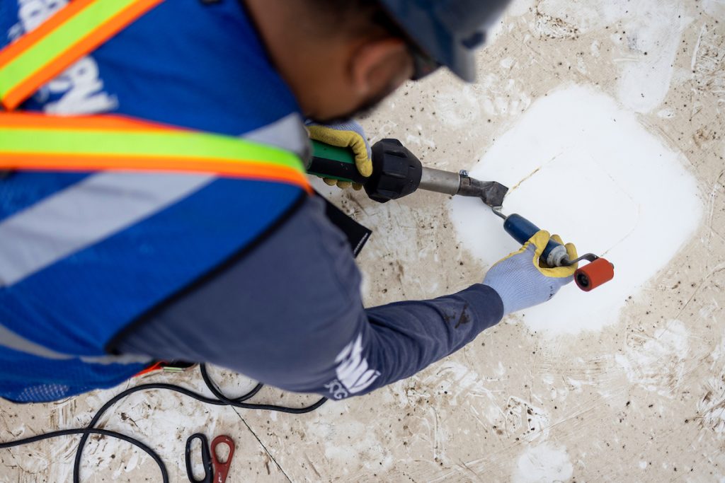 Man patching a hole on a roof. smartCARE roof maintenance.