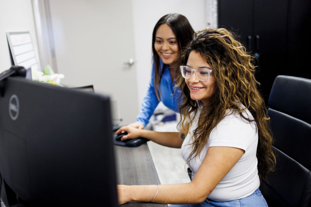 Two women at a desk looking at a computer - Contact